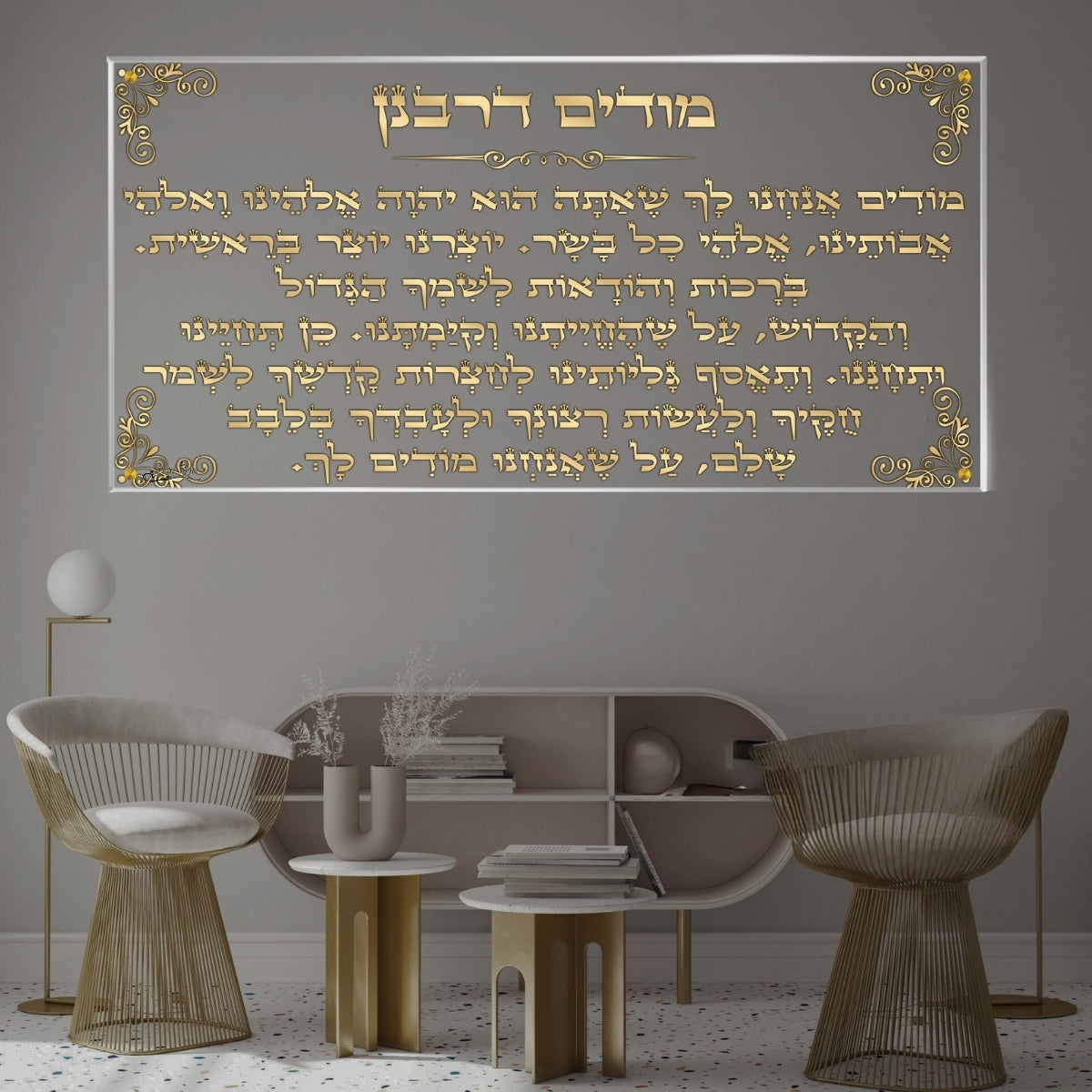 תמונת זכוכית של מודים דרבנן עם טקסט זהוב על רקע אפור, תלויה מעל פינת ישיבה מודרנית ומעוצבת.